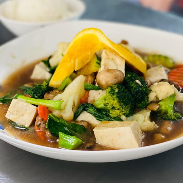 Asian-fusion tofu and mixed vegetables in a savory sauce, garnished with an orange slice.