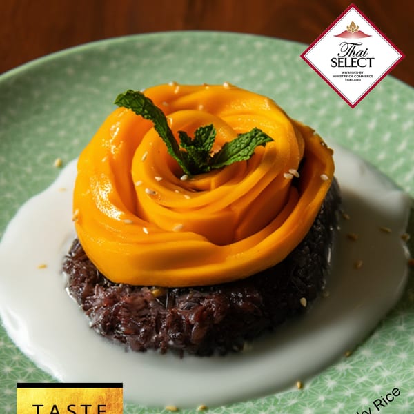 Mango sticky rice dessert with mango slices arranged like a rose, mint, and sesame seeds.